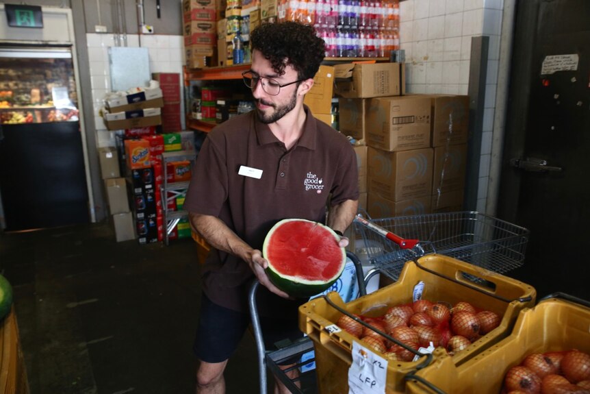 A supermarket employee restocks the fruit and vegetable section.