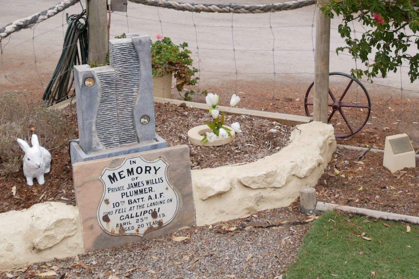 A plaque in memory of Private James Willis Plummer in front of a small garden.