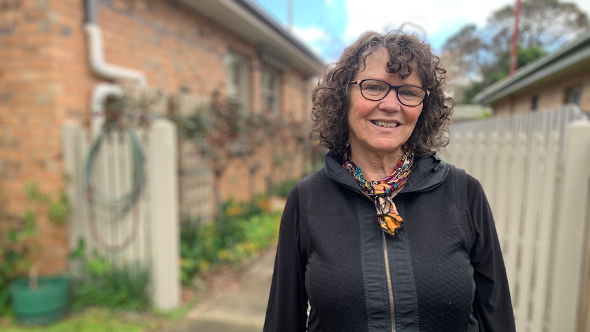 Bronwyn Stretton smiling at the camera in a portrait taken outside a one-storey brick home.