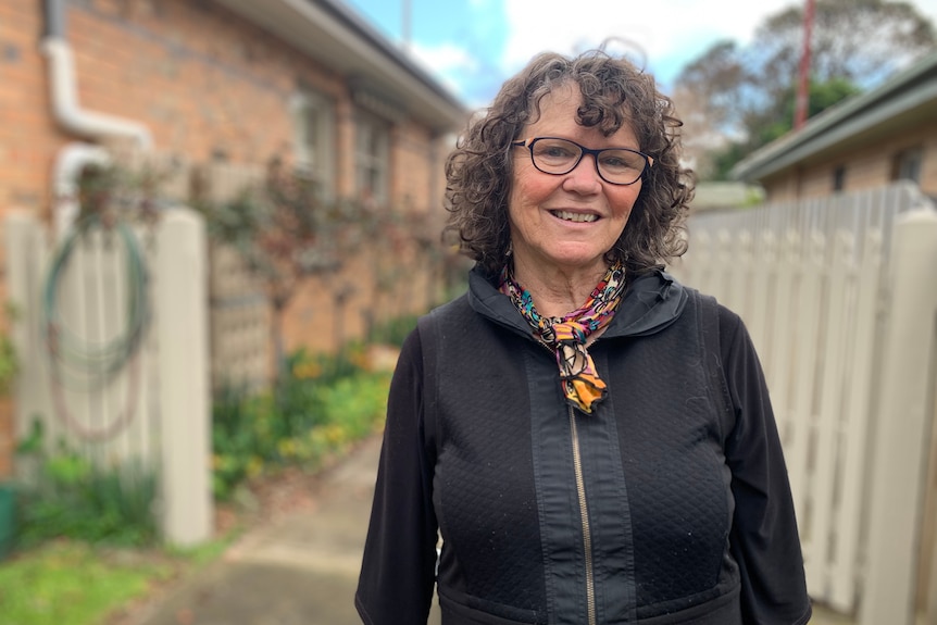 Bronwyn Stretton smiling at the camera in a portrait taken outside a one-storey brick home.