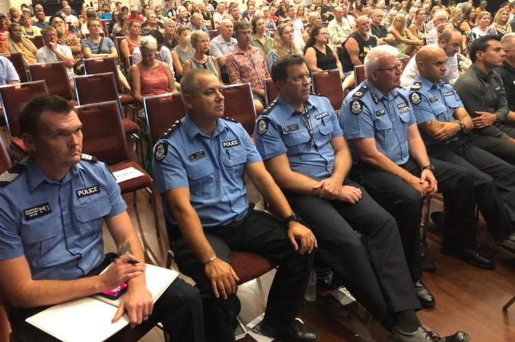 Police sit in front of a crowd.