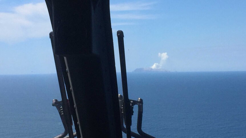 A plume of white smoke can be seen in the distance through the windshield of a helicopter, after a deadly volcano eruption