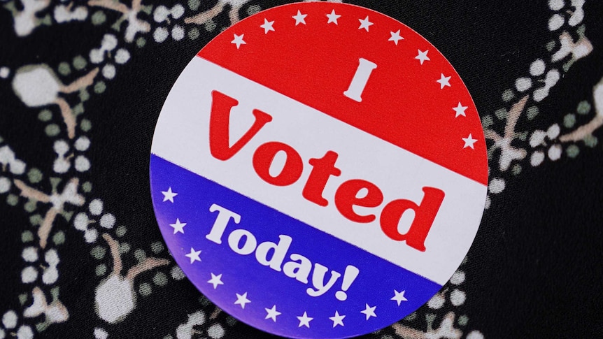 A red white and blue sticker saying "I voted today" pinned to some black, white, green and brown fabric