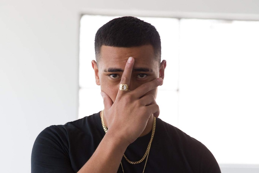 YP, a member of drill music group OneFour, covers his face with his hand.