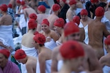 Post-dip exhilaration for nude swim participants in red caps.