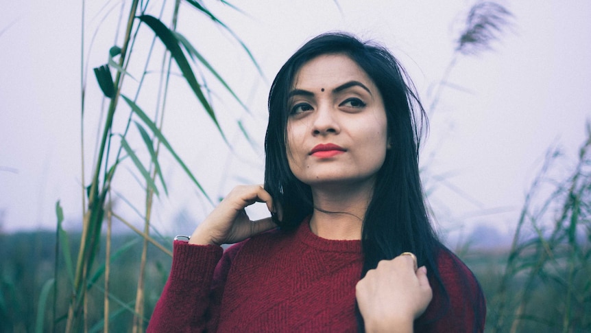 A young woman (not the author) of south-Asian background looks pensively into the distance.
