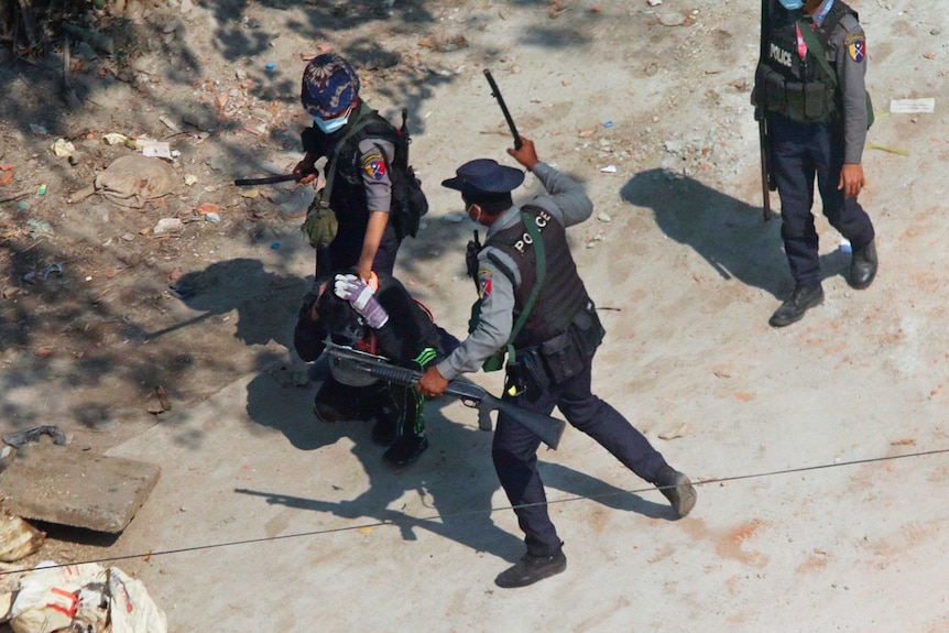 Riot police officers hold down a protester