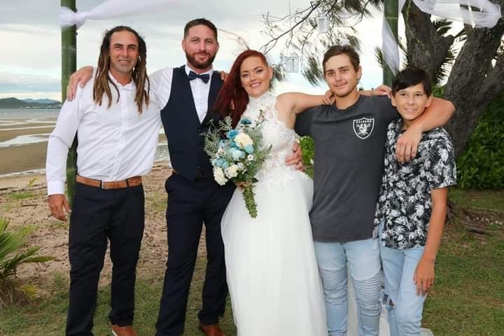 a family dressed for a formal affair stand arm in arm looking at the camera