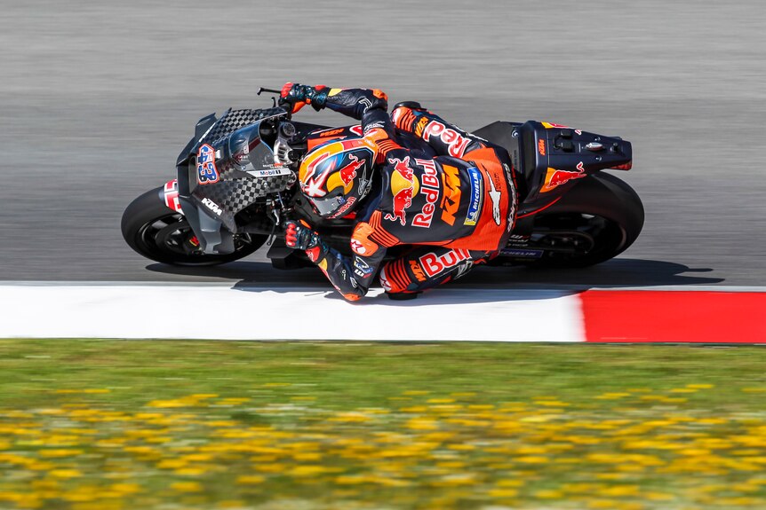 Jack Miller rides a bike leaning over and touching his knee against the tarmac