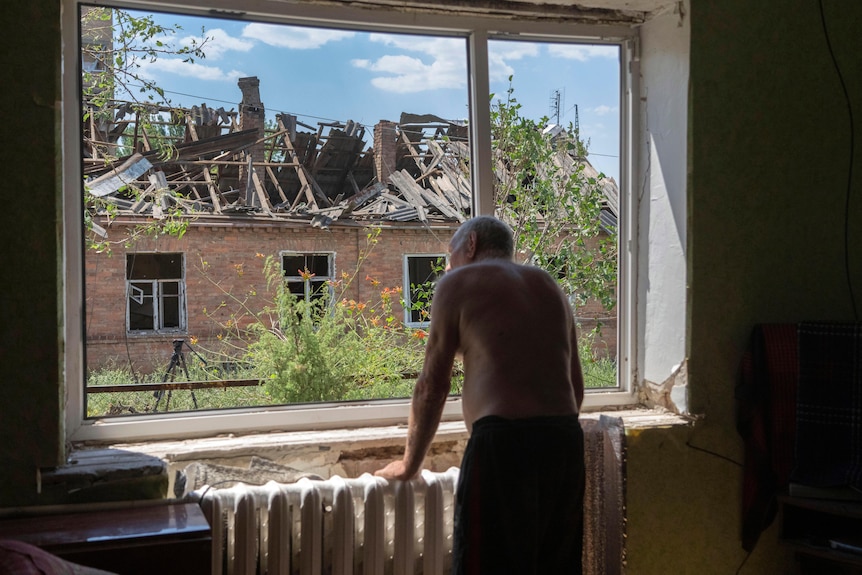 Man in Bakhmut looks through his destroyed window