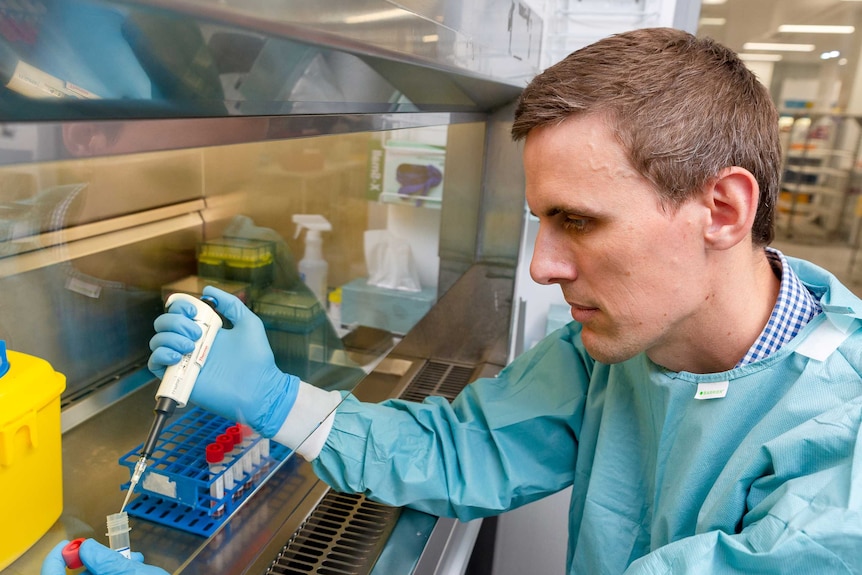 Male scientist using syringe