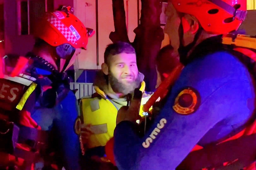 A man smiles at a camera with SES officers around him 