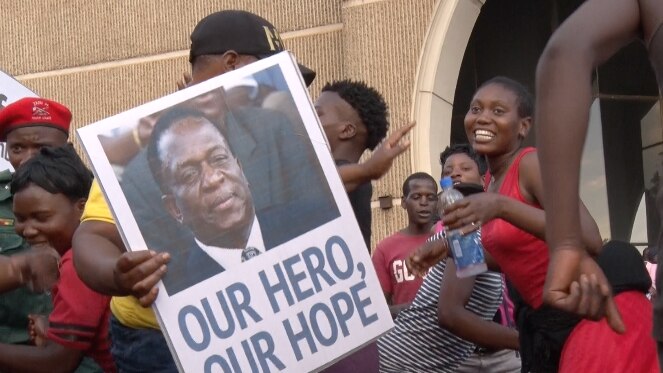 A person holds a poster with a picture of Emmerson Mnangagwa