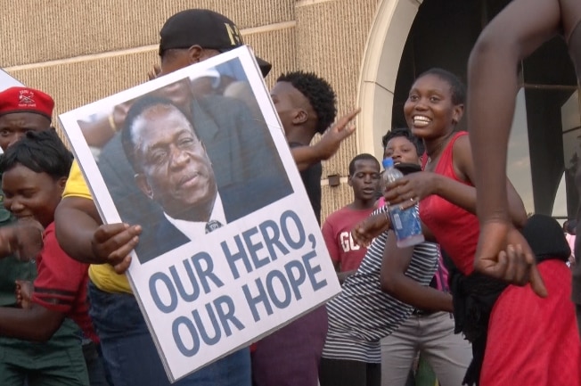 A person holds a poster with a picture of Emmerson Mnangagwa