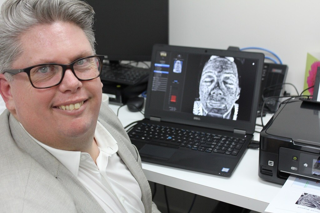 Professor Michael Kimlinsits in front of UV camera on a desk.
