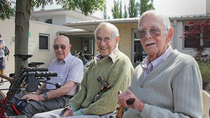 Elderly men with walking sticks sitting outside an aged care facility in Canberra.