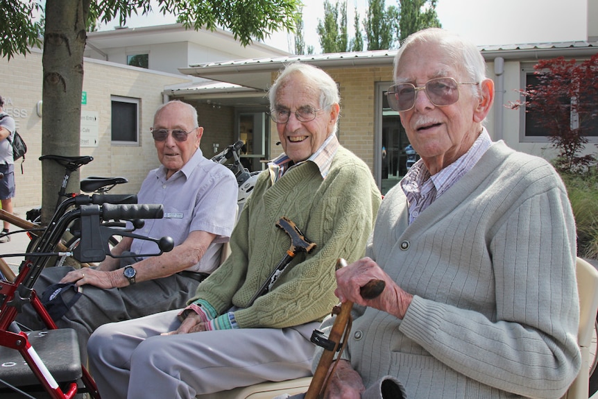 Elderly men with walking sticks sitting outside an aged care facility in Canberra.