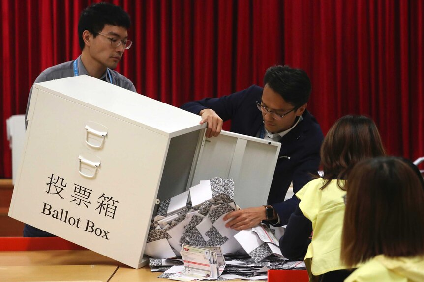 Election workers empty a ballot box to count votes at a polling station in Hong Kong.