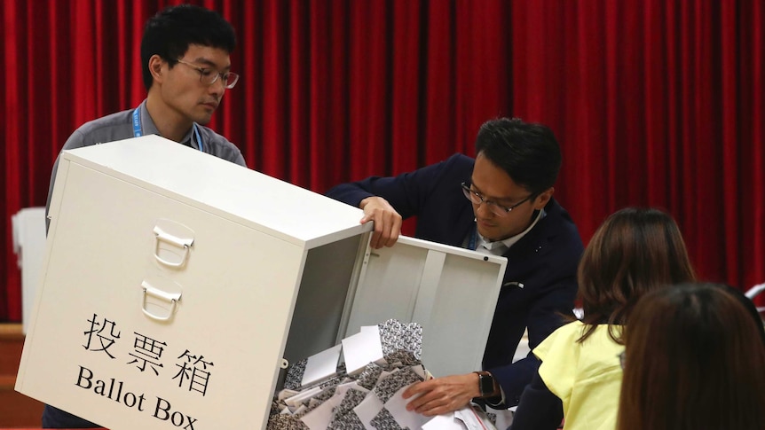 Election workers empty a ballot box to count votes at a polling station in Hong Kong.