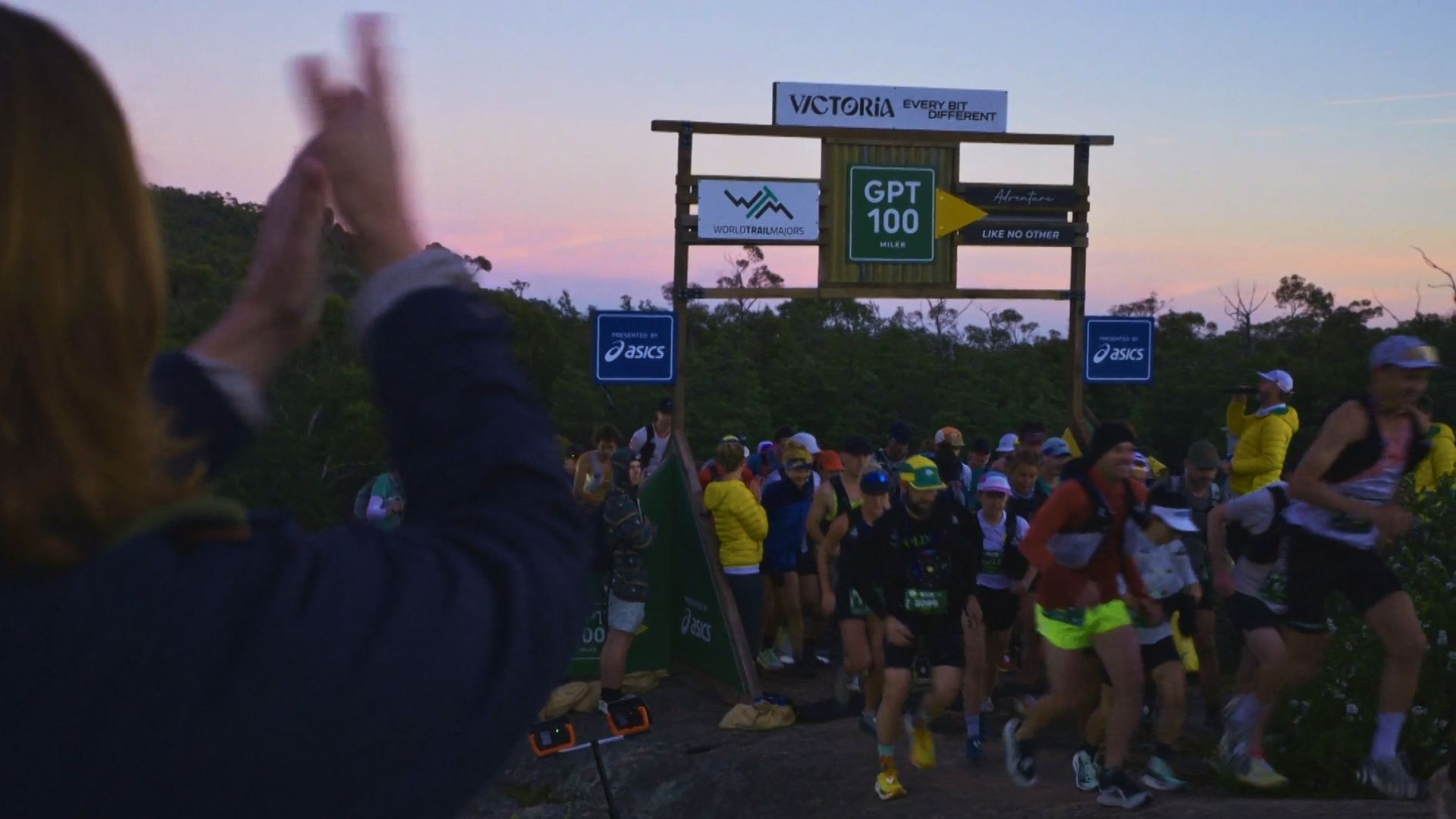 A large group of runners begin their race on rocky terrain in the early morning.