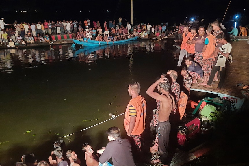 La gente guarda il lavoro di salvataggio dopo che una nave passeggeri che trasportava più di 100 persone è affondata