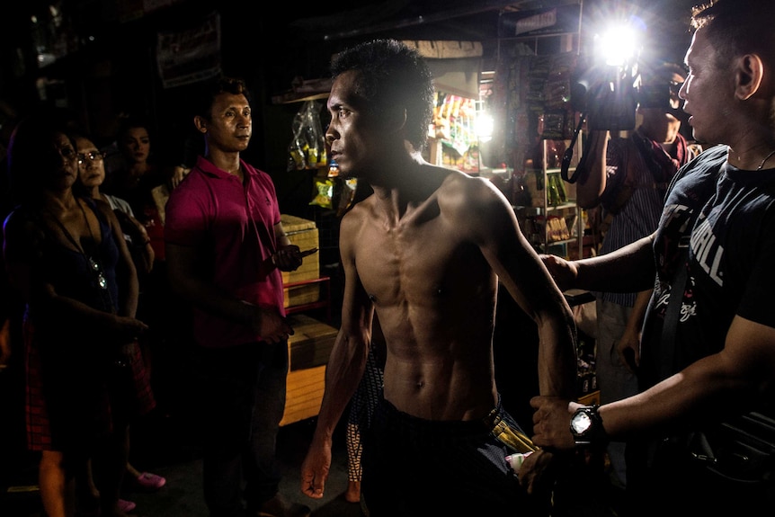 A half naked man detained by policemen in Manilla