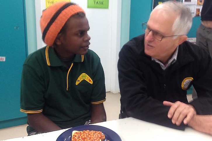 Participant in Yalata breakfast program speaks with Malcolm Turnbull as they sit at a table with baked beans in front of them