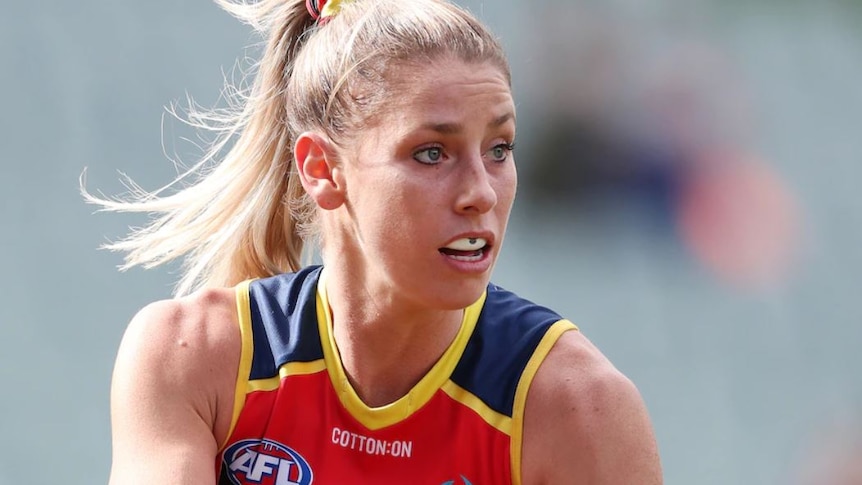 A young woman with blonde hair in a football guernsey