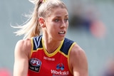 A young woman with blonde hair in a football guernsey