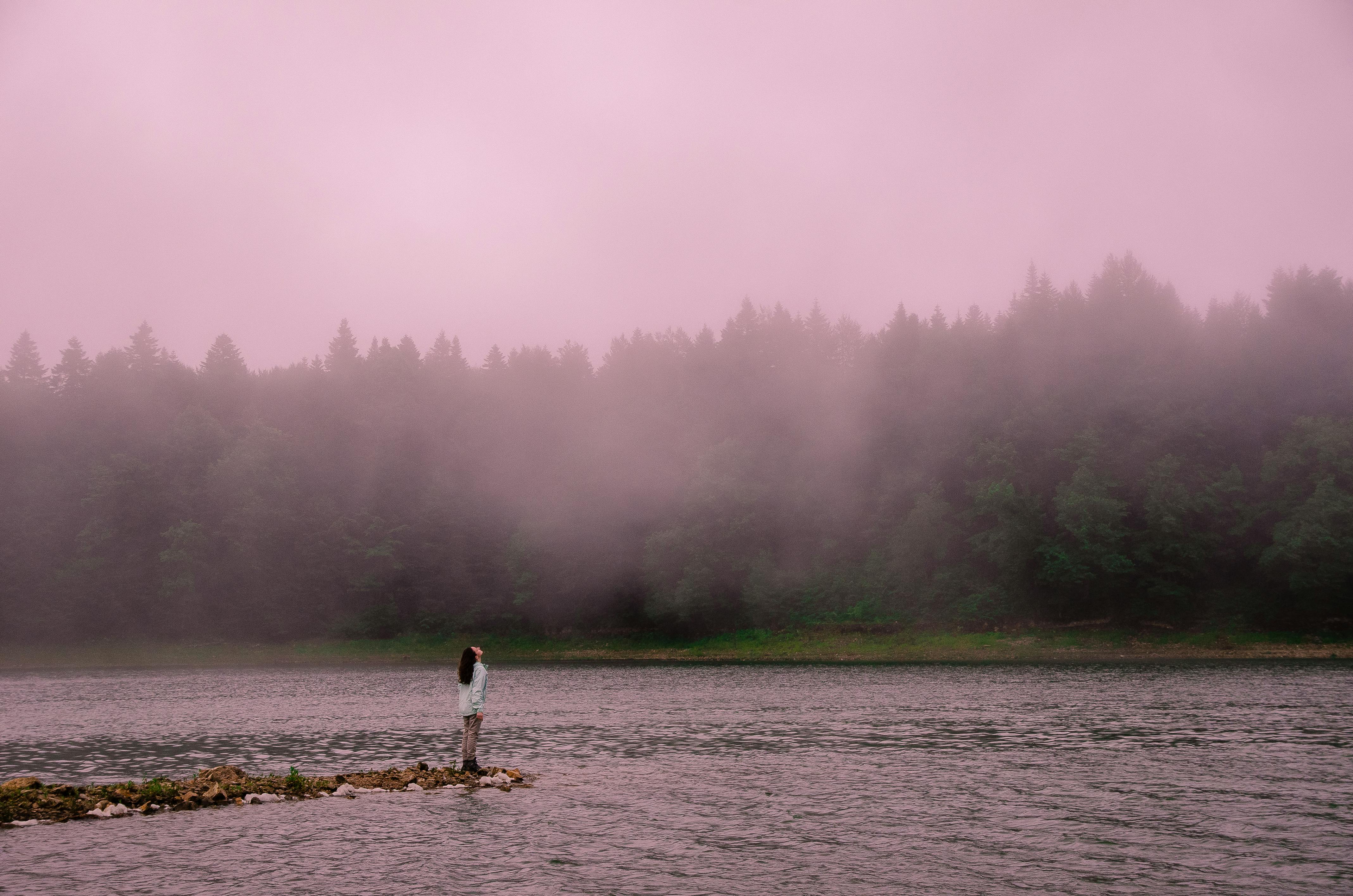 woman standing by misty lake 