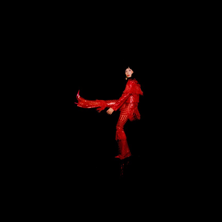 a woman in a red suit kicks her leg up