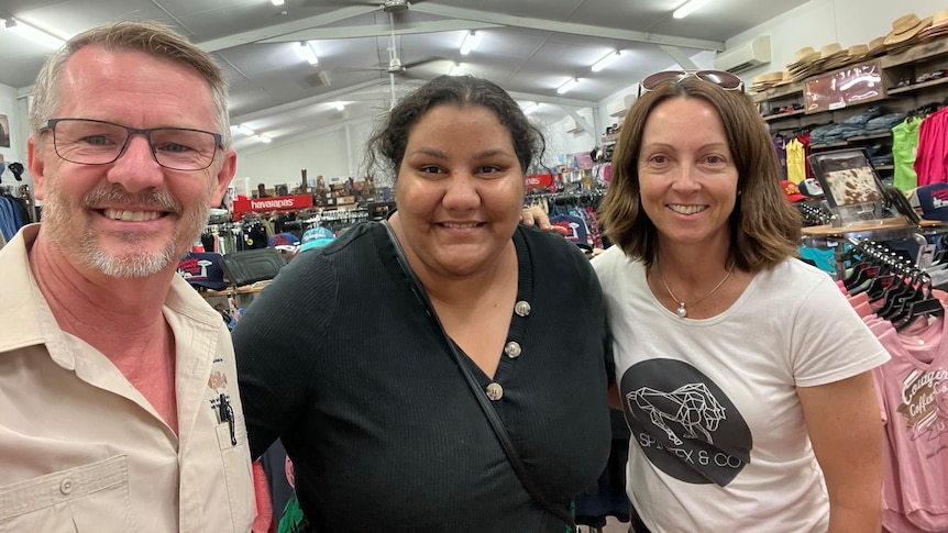 Man and two women in a retail store smiling at the camera