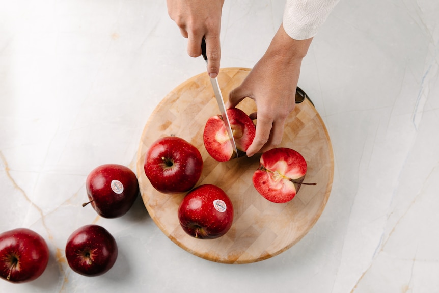 An apple being cut on a cutting board