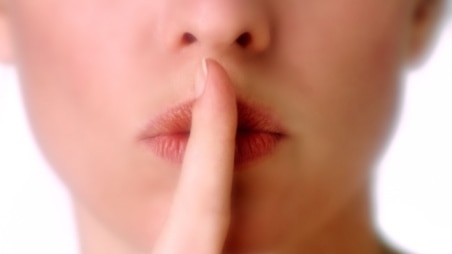 Close-up of woman with index finger to lips, making hush sign (Brand X Pictures: Thinkstock)