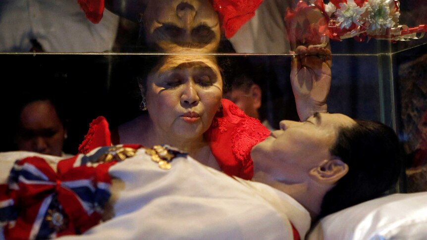 Former first lady Imelda Marcos kisses the glass coffin of her husband, late president Ferdinand Marcos.