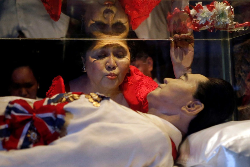 Imelda Marcos kisses the glass coffin of her husband Ferdinand Marcos