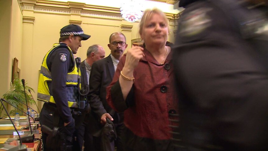 A man is surrounded by police and media.