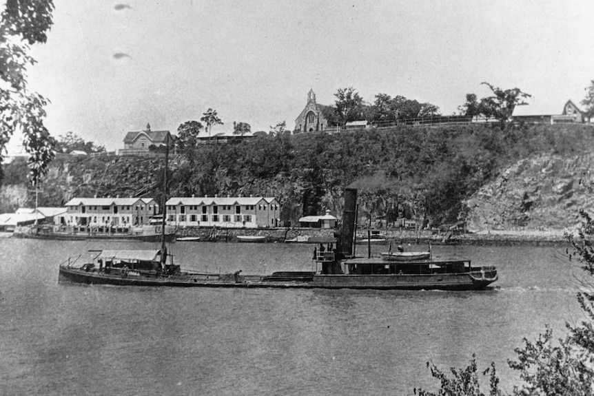 A historical photo of a steamship near old buidlings.