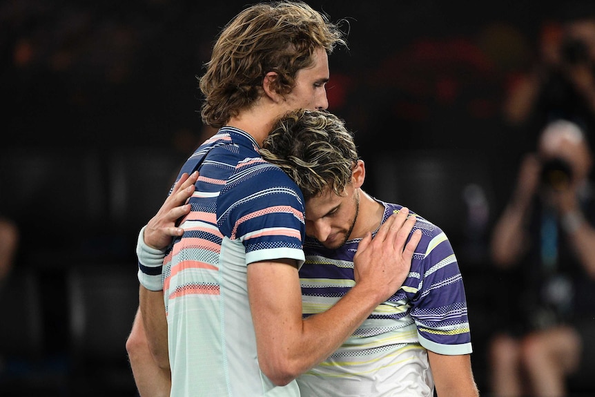 Two male tennis players embrace at the net as they congratulate each other at the Australian Open.