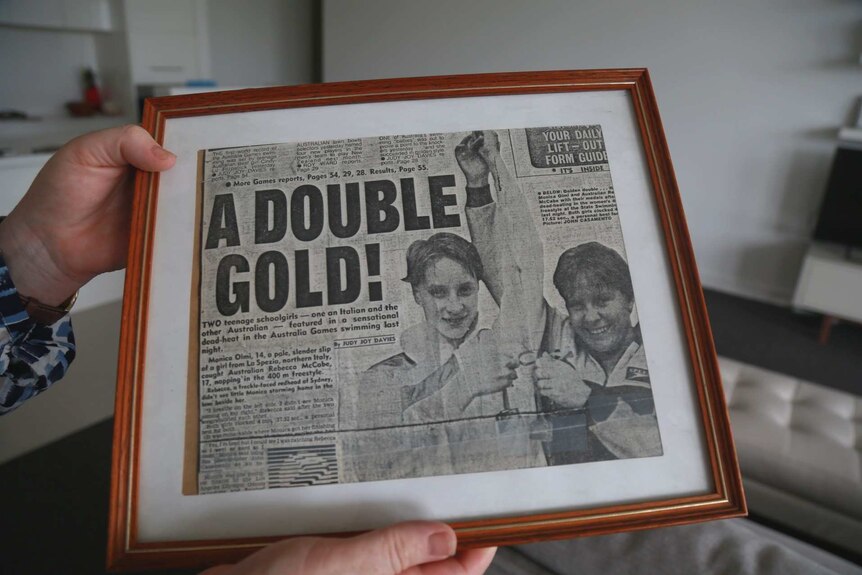 Old newspaper clipping of a young girl holding a medal from a swimming race.