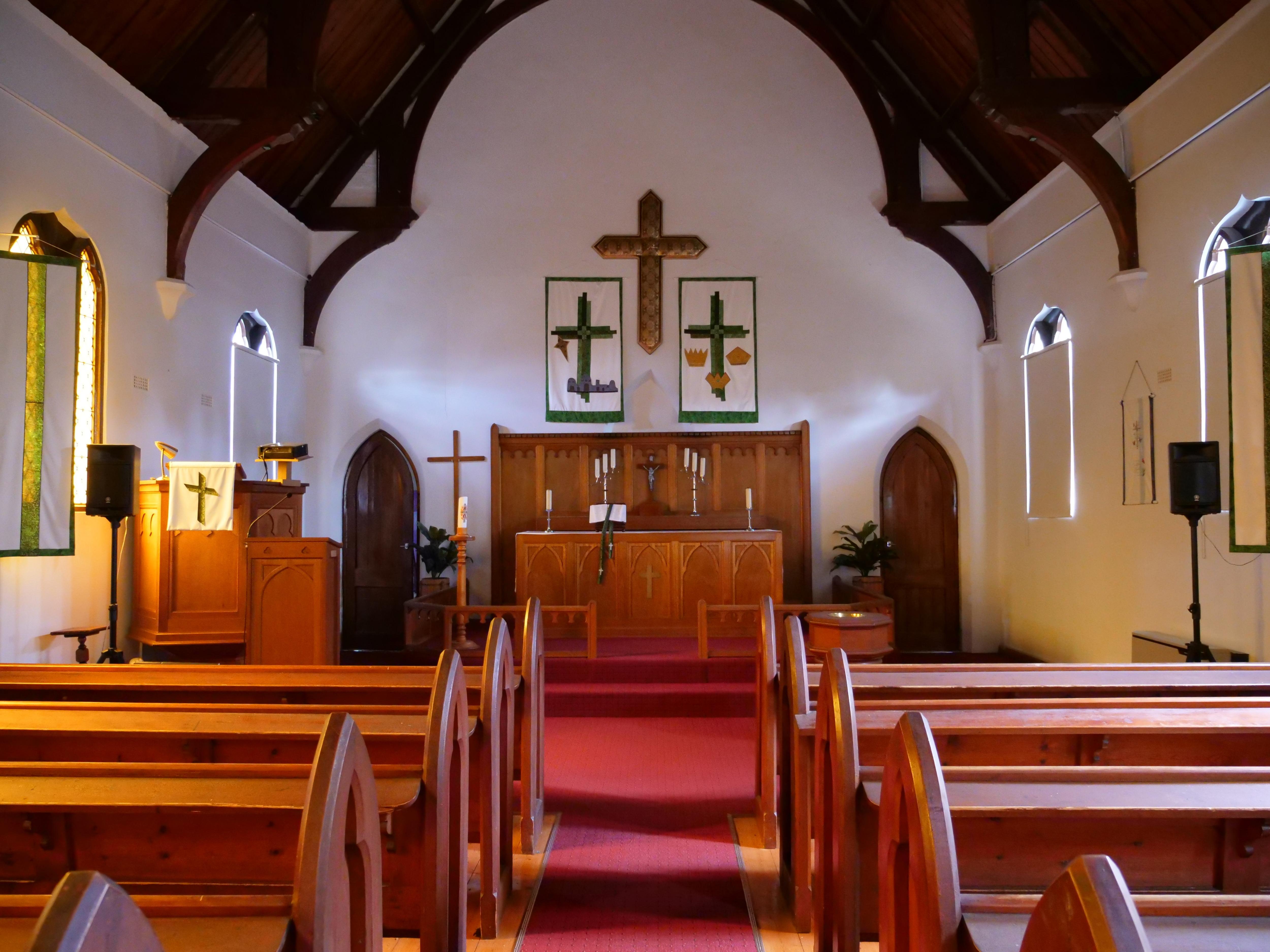 El interior de una pequeña iglesia con bancos a ambos lados de una isla.