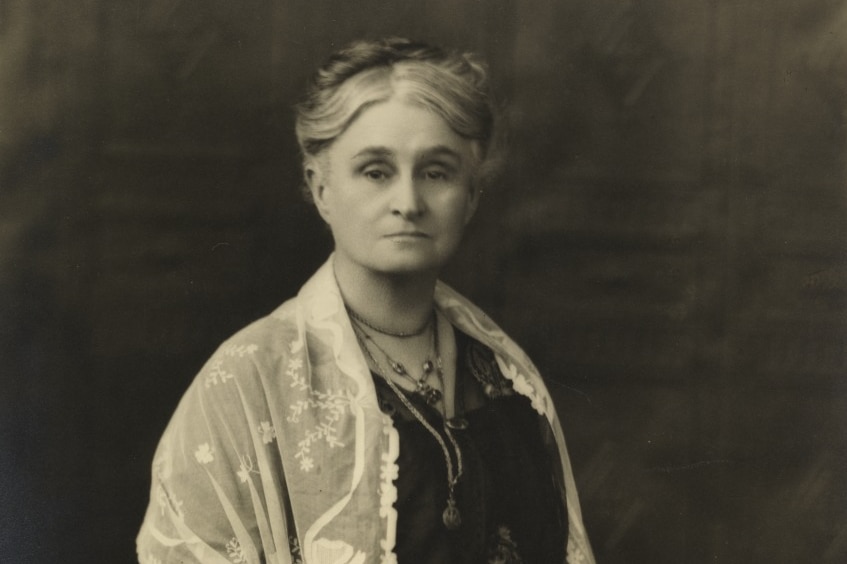 Old black and white photo of Edith Cowan, unsmiling, hair in a neat bun, wearing black dress with white lace shawl.