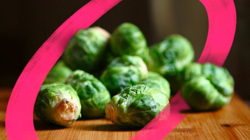 Whole brussels sprouts sit on a chopping board, for a story about cooking brussels sprouts and making them taste delicious.