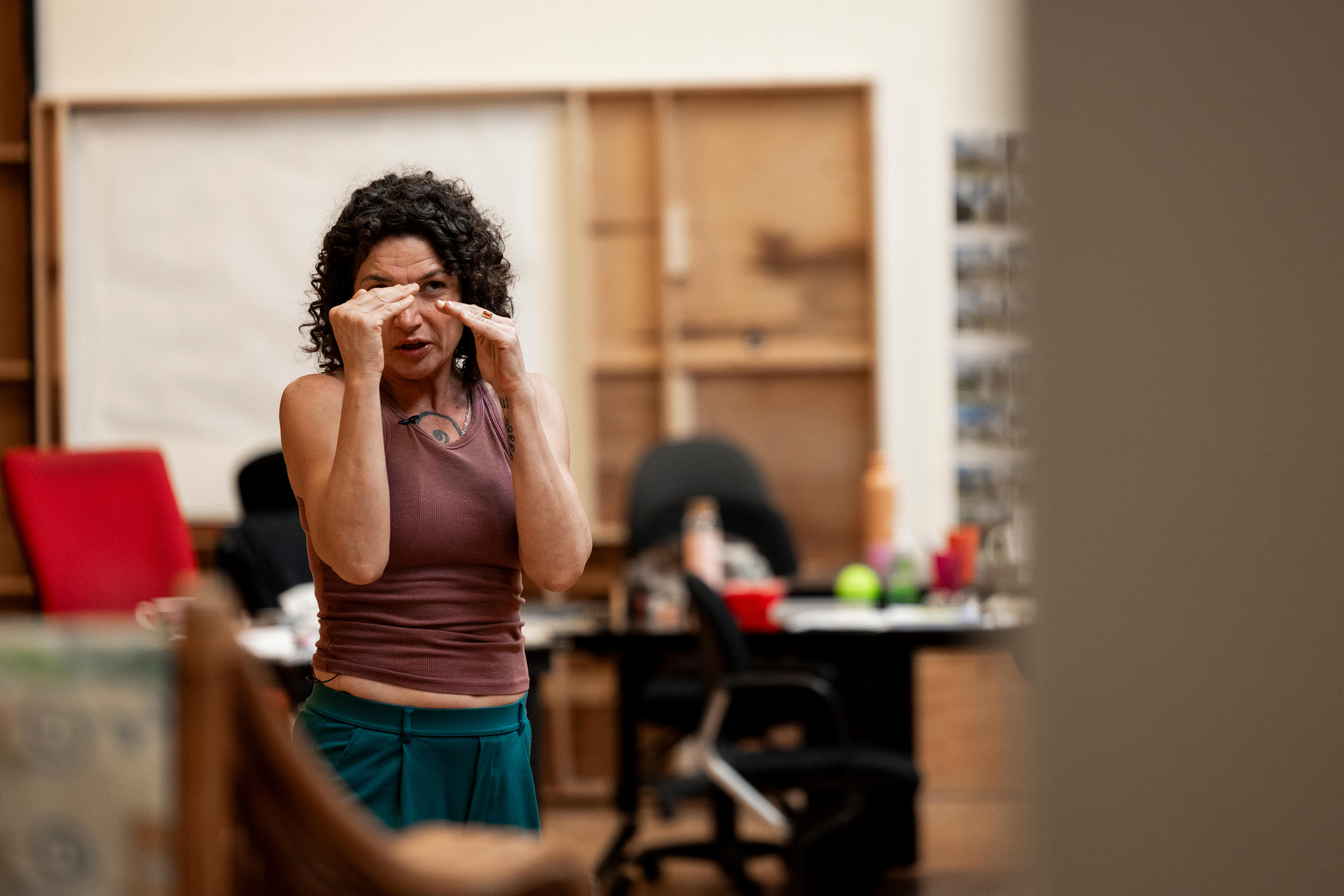 A young woman holds up her hands in a square during a rehearsal.