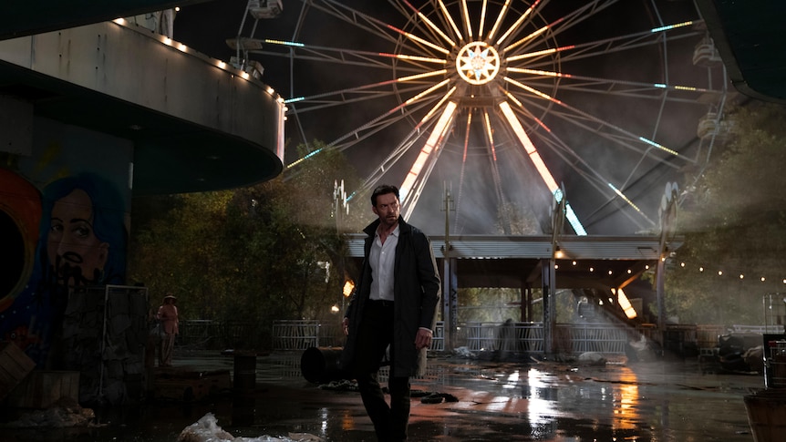 A man standing behind a Ferris wheel.