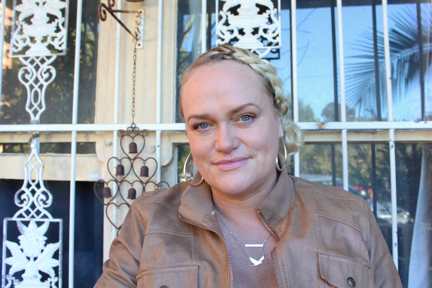 Tansy Mayhew sitting in front of a window on her front porch in Maroubra.