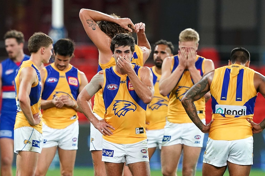A group of West Coast Eagles AFL players stand around looking disappointed after their loss to the Western Bulldogs.