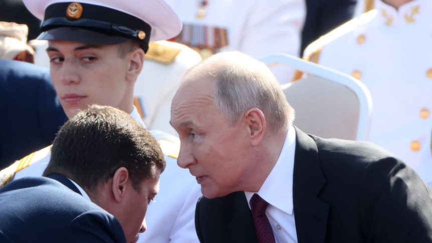 Russian President Vladimir Putin talks to military officials at a navy parade