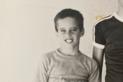 A young boy smiles in a black and white photo.