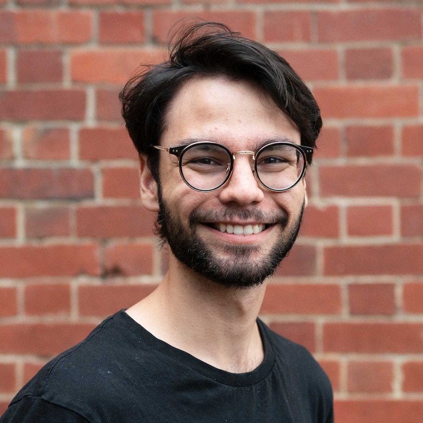 A young man in glasses smiles